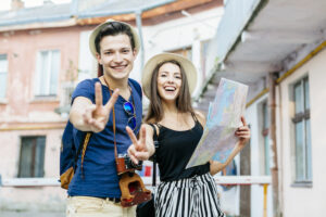couple giving peace signs with a map walking happily through a town