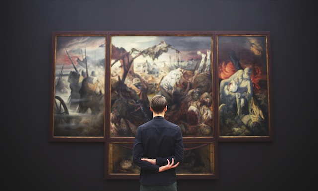 man standing looking at a painting in a museum.