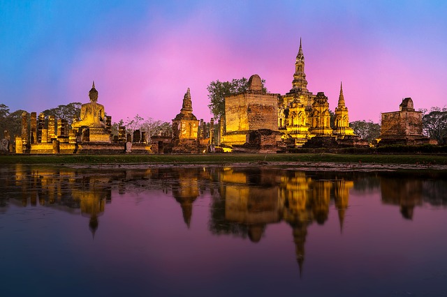 Pink sunset near water and temples in Thailand, a perfect solo spot.