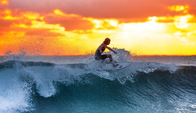 Man surfing in Bali ocean during sunset.
