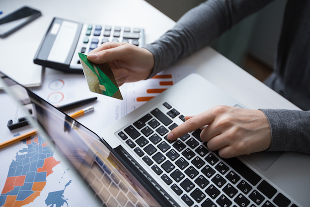 person typing in their credit card information into a computer.