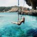 woman swinging into blue waters in Spain post break up