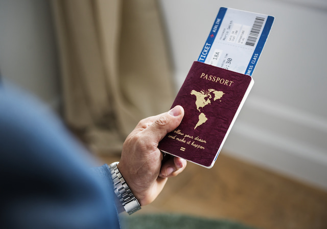 person holding a passport and boarding pass ticket, ready to avoid the long wait in security.