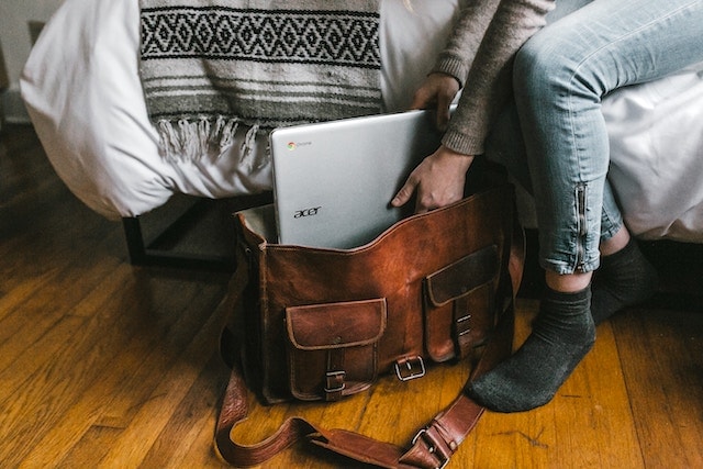 person packing a laptop into his carry-on bag. 