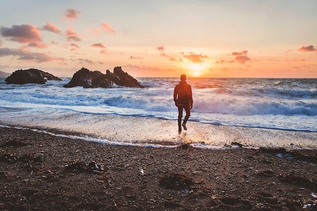 man walking on beach, with zero crowds for the perfect shot during sunrise. 