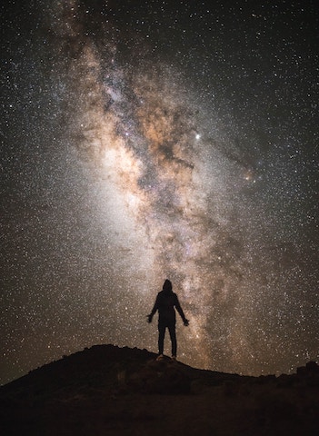 shot atop mauna kea. silhouette of man in front of starry night and the milky way.